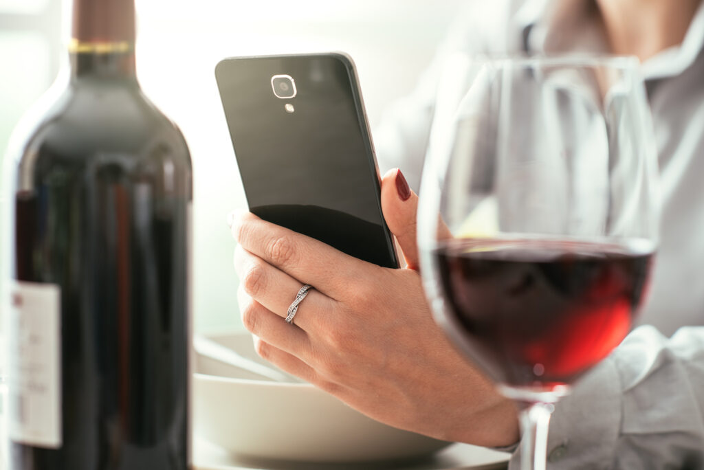woman drinking wine while browsing online